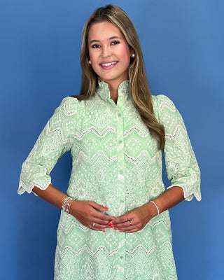 Woman wearing a green patterned dress against a blue background