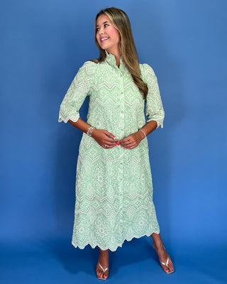 Woman wearing a light green patterned dress against a blue background