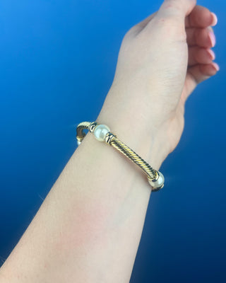 Shop the Gold & Pearl Bangle featuring a twisted gold-tone design, faux pearl accents, and a secure hinged closure for timeless elegance.