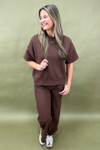 Woman wearing a brown outfit against a green background