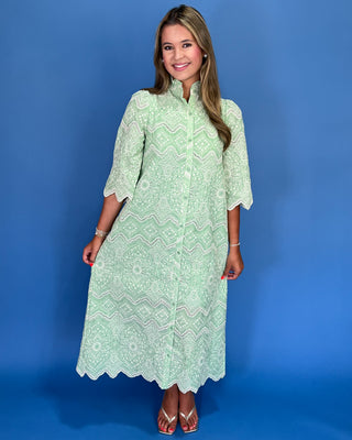 Woman wearing a light green dress with a pattern against a blue background