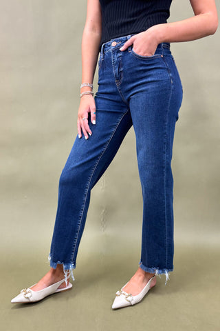 Person wearing blue jeans and a black top on a beige background