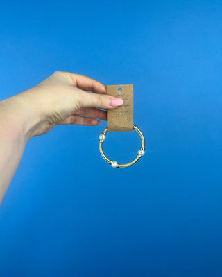 Shop the Gold & Pearl Bangle featuring a twisted gold-tone design, faux pearl accents, and a secure hinged closure for timeless elegance.