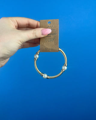 Shop the Gold & Pearl Bangle featuring a twisted gold-tone design, faux pearl accents, and a secure hinged closure for timeless elegance.