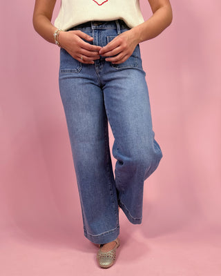 Person wearing blue jeans on a pink background