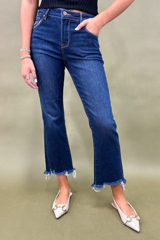 Person wearing blue jeans and white shoes on a beige background