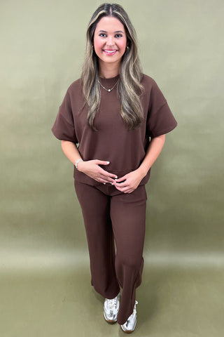 Woman wearing a brown outfit standing against a plain background
