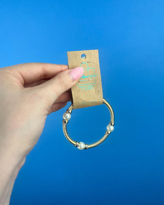 Shop the Gold & Pearl Bangle featuring a twisted gold-tone design, faux pearl accents, and a secure hinged closure for timeless elegance.