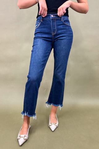 Person wearing blue jeans and white shoes on a beige background