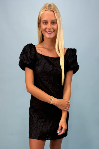 Woman wearing a black dress against a light blue background