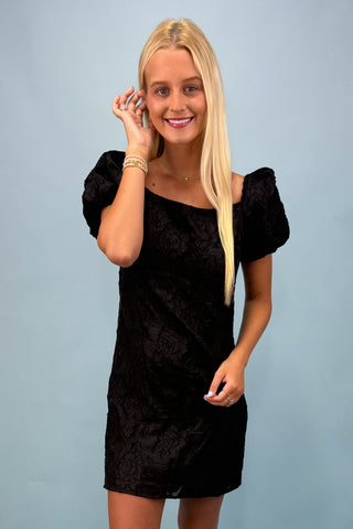 Woman wearing a black dress against a light blue background