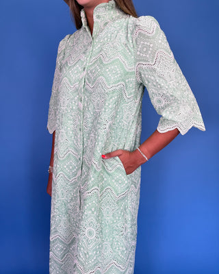 Woman wearing a light green dress with white patterns against a blue background