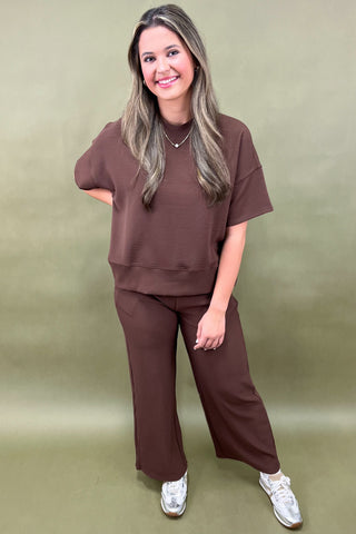 Woman wearing a brown outfit against a green background