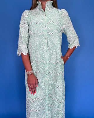 Person wearing a light green patterned dress against a blue background