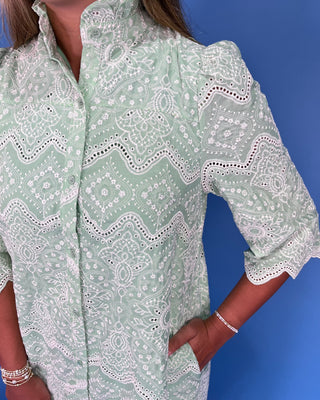 Person wearing a green patterned dress against a blue background