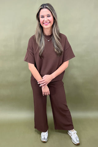 Woman wearing a brown outfit against a green background