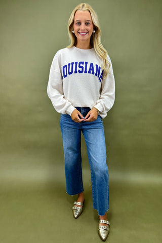 Woman wearing a white sweatshirt with 'LOUISIANA' printed on it against a green background