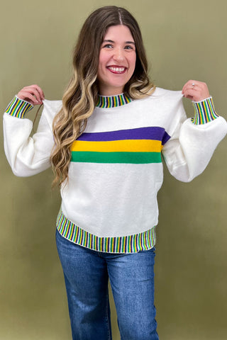 Woman wearing a white sweater with colorful stripes on a beige background