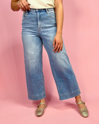 Person wearing blue jeans on a pink background