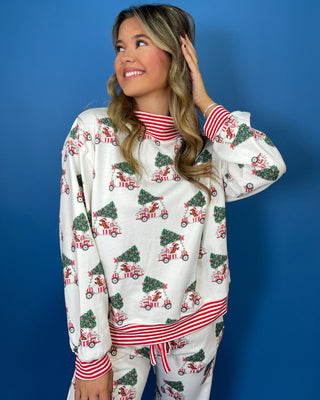 White Christmas pajama set with festive golf cart and Christmas tree print, red striped trim, long sleeves, and jogger pants.