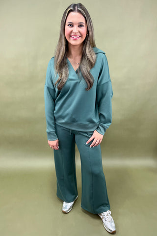 Woman wearing a teal outfit against a beige background