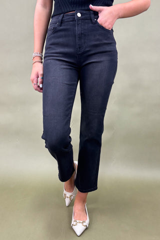 Person wearing dark blue jeans and white shoes on a plain background