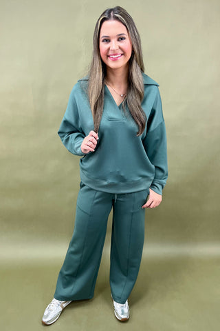 Woman wearing a teal tracksuit against a beige background
