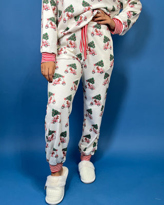 White Christmas pajama set with festive golf cart and Christmas tree print, red striped trim, long sleeves, and jogger pants.