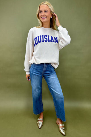 Woman wearing a white sweatshirt with 'LOUISIANA' printed on it against a green background