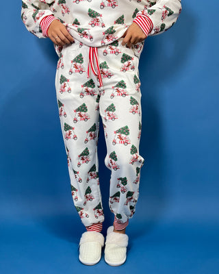 White Christmas pajama set with festive golf cart and Christmas tree print, red striped trim, long sleeves, and jogger pants.
