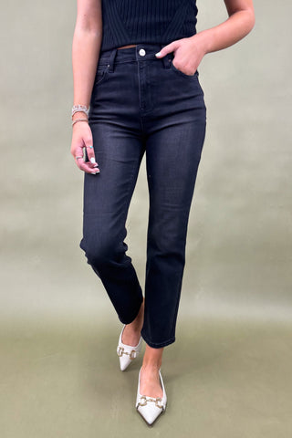Person wearing dark blue jeans and white shoes on a plain background