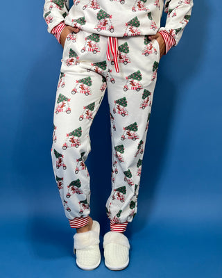 White Christmas pajama set with festive golf cart and Christmas tree print, red striped trim, long sleeves, and jogger pants.