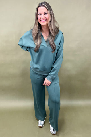Woman wearing a teal outfit against a beige background