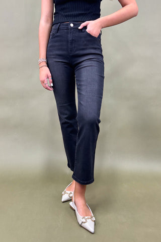 Person wearing dark blue jeans and white shoes on a plain background