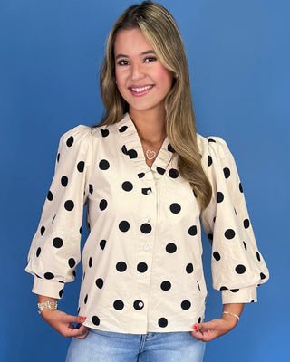 Woman wearing a polka dot blouse against a blue background