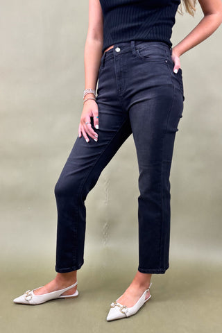 Person wearing dark blue jeans and a black top on a beige background