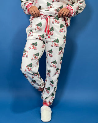 White Christmas pajama set with festive golf cart and Christmas tree print, red striped trim, long sleeves, and jogger pants.