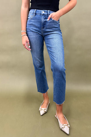 Person wearing blue jeans and white shoes on a plain background