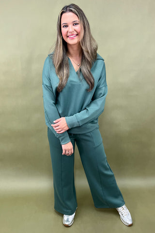 Woman wearing a teal outfit against a beige background