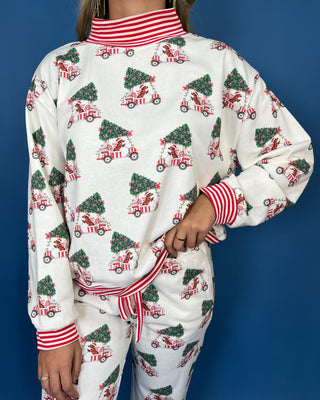 White Christmas pajama set with festive golf cart and Christmas tree print, red striped trim, long sleeves, and jogger pants.