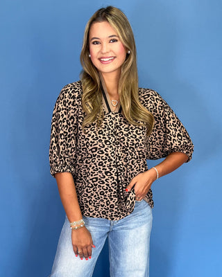 Woman wearing a leopard print top and jeans against a blue background
