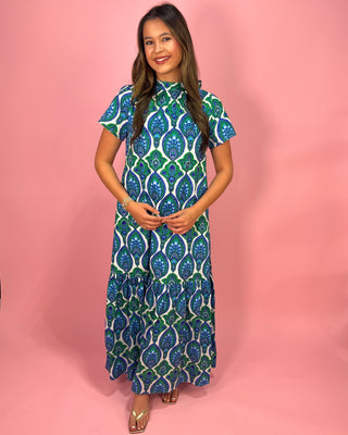 Woman wearing a green and blue patterned dress on a pink background