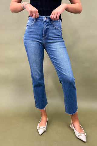 Person wearing blue jeans and white shoes on a plain background