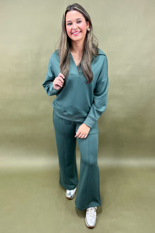 Woman wearing a teal tracksuit against a beige background