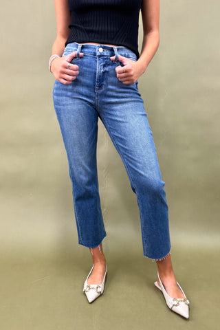 Person wearing blue jeans and a black top against a green background