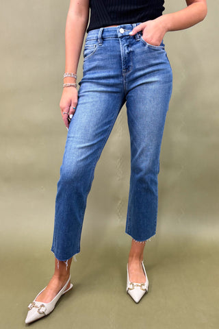 Person wearing blue jeans and white shoes on a green background