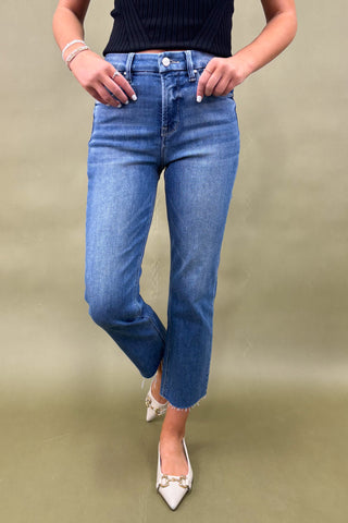 Person wearing blue jeans and white shoes on a beige background
