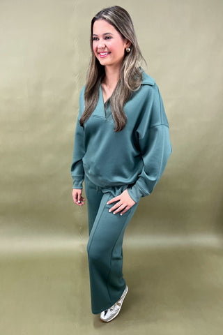 Woman wearing a teal tracksuit against a beige background