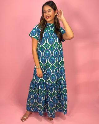 Woman wearing a blue and green patterned dress against a pink background