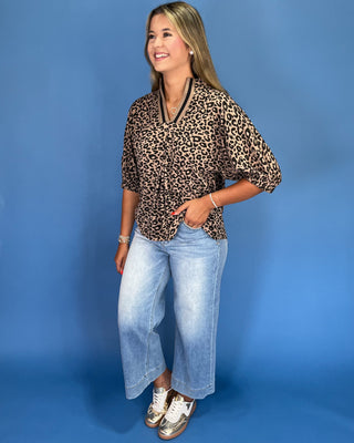 Woman wearing a leopard print top and jeans against a blue background